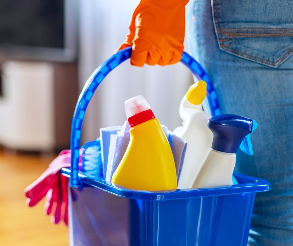 A person is holding a blue bucket full of cleaning supplies