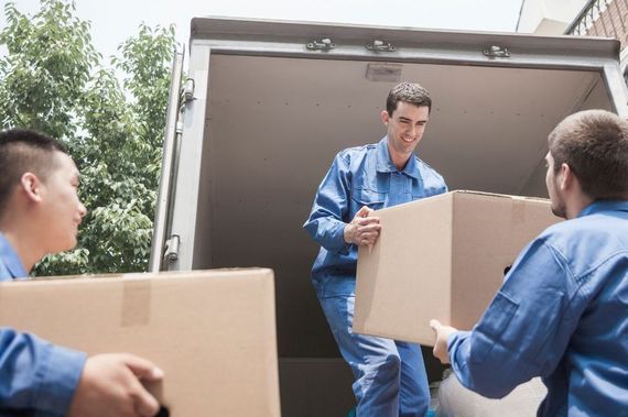 A man and a woman are sitting in a cardboard box holding keys to their new home.