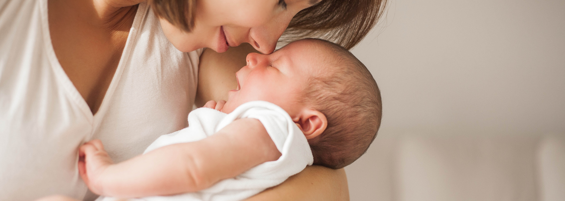 Picture of a baby, cradled in its mother's arms.