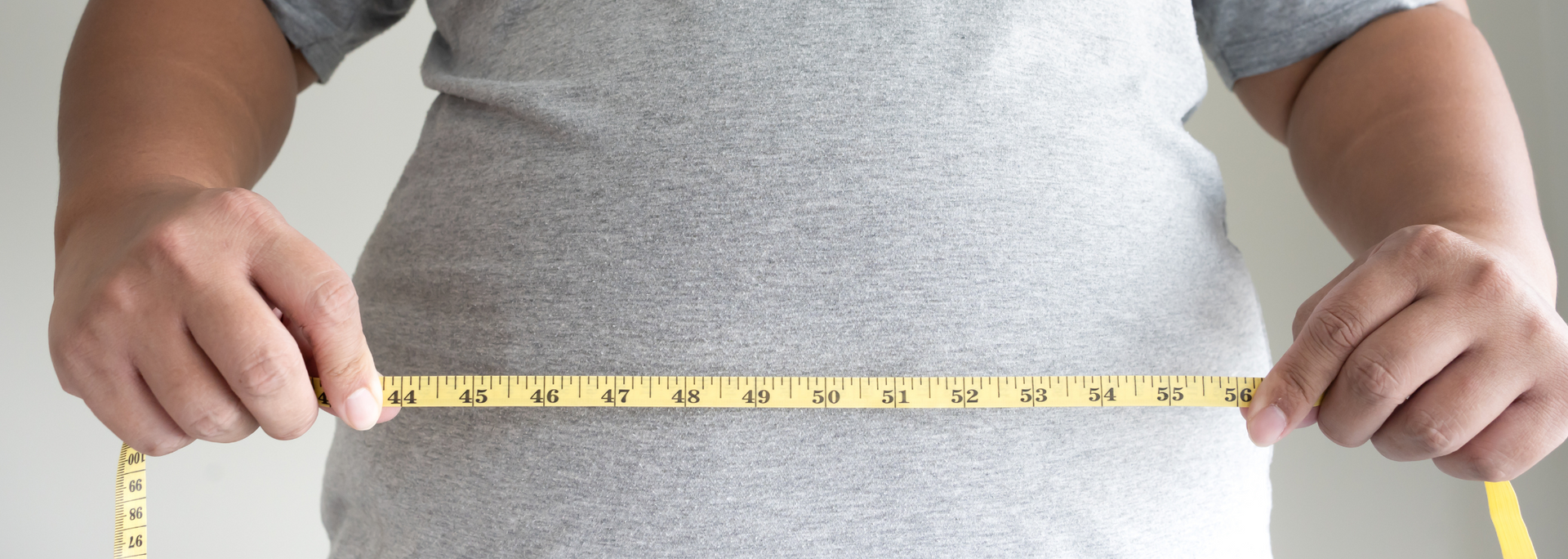 Picture of a person holding a measuring tape around their waist.