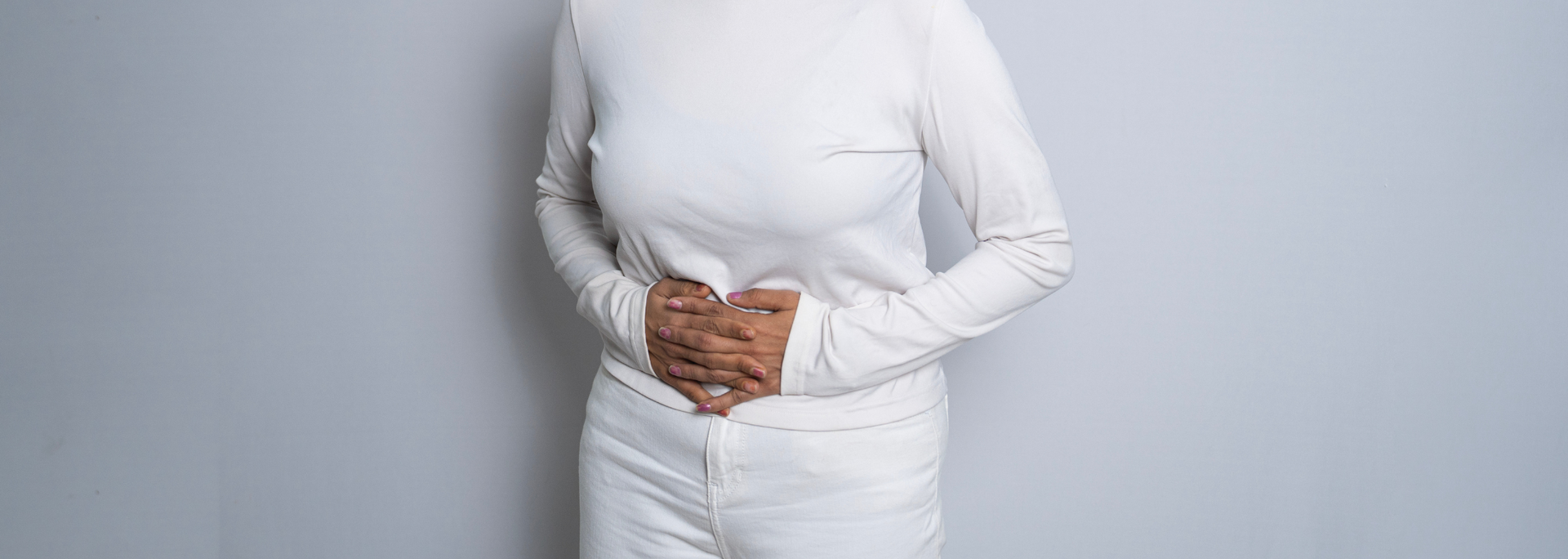Picture of a person holding their hands at their lower stomach.