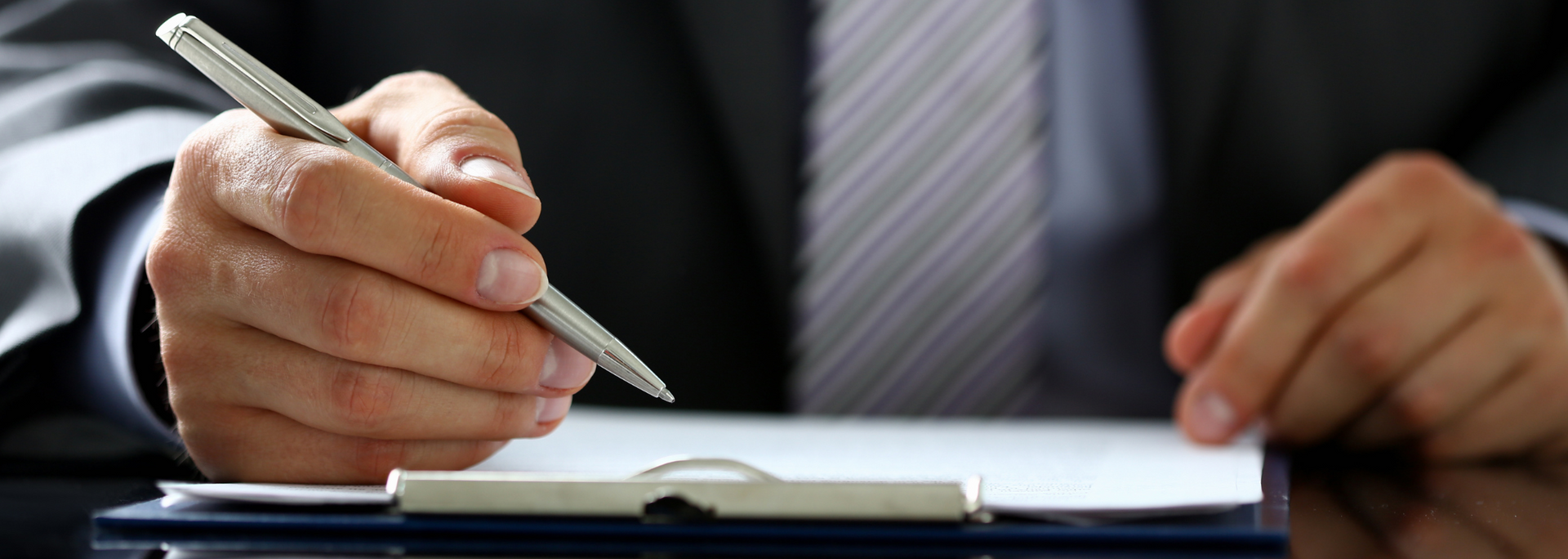 Picture of a professional-looking person writing on a clipboard.