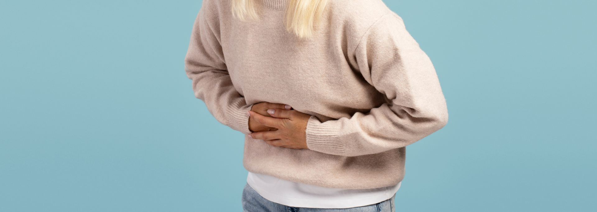 Picture of a woman holding her stomach experiencing nausea.