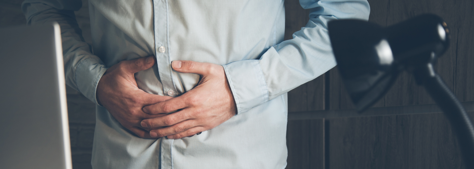 Picture of person holding belly as if experiencing gastrointestinal distress.