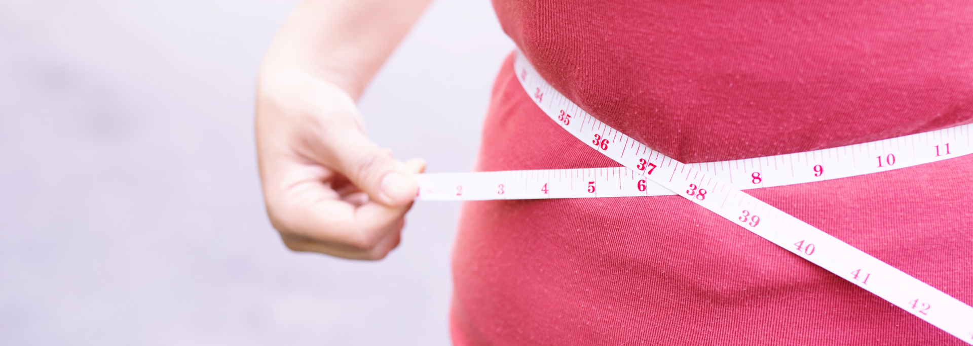 Picture of someone holding a tape measure around their waist.