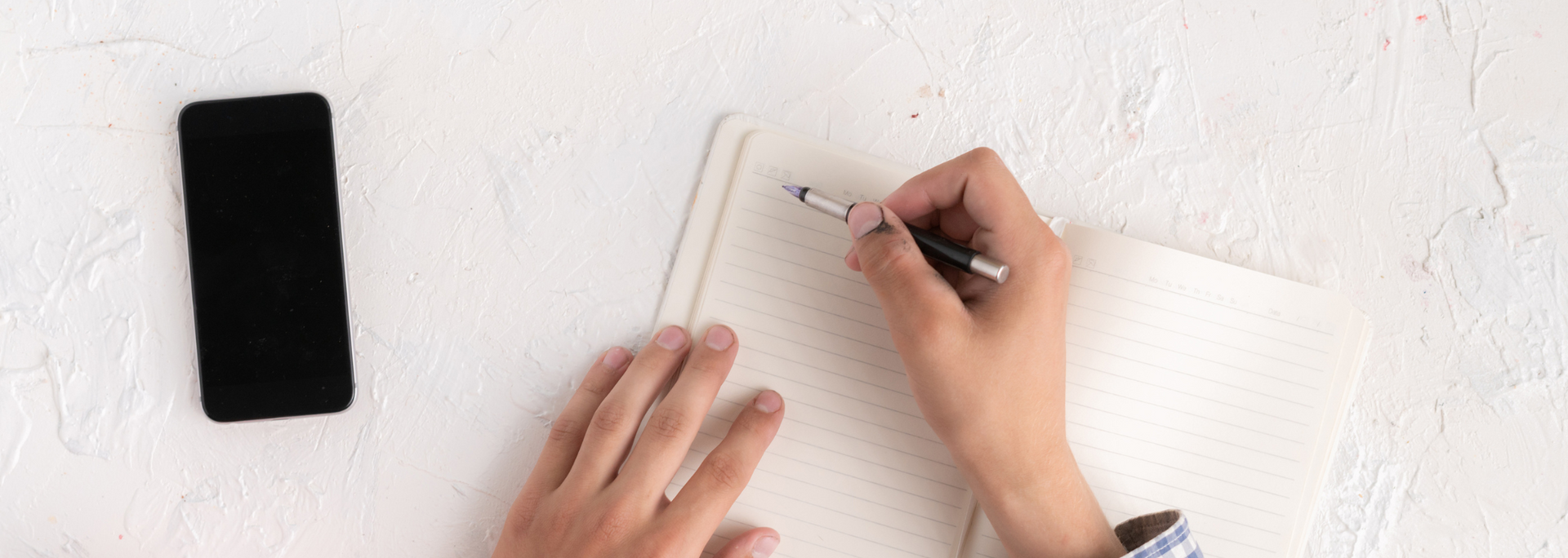 Picture of someone writing on a notebook.