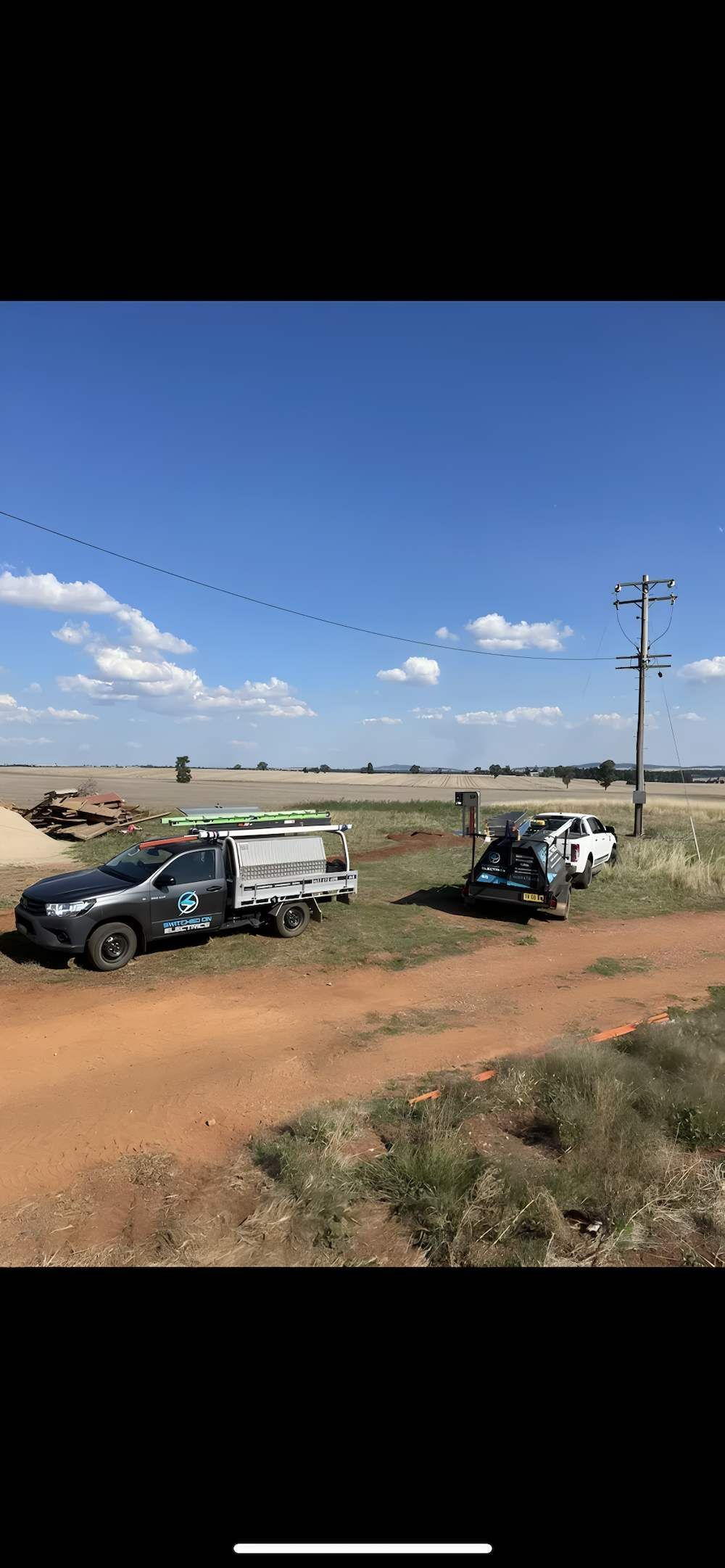 Two Trucks on a Dirt Road in a Field With a Utility Pole — Switched On Electrics in Wagga Wagga, NSW