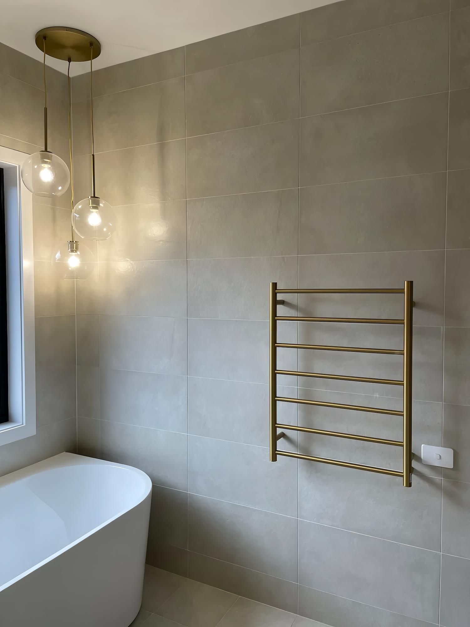 Bathroom With a White Tub, Gold Towel Warmer, and Globe — Switched On Electrics in Wagga Wagga, NSW