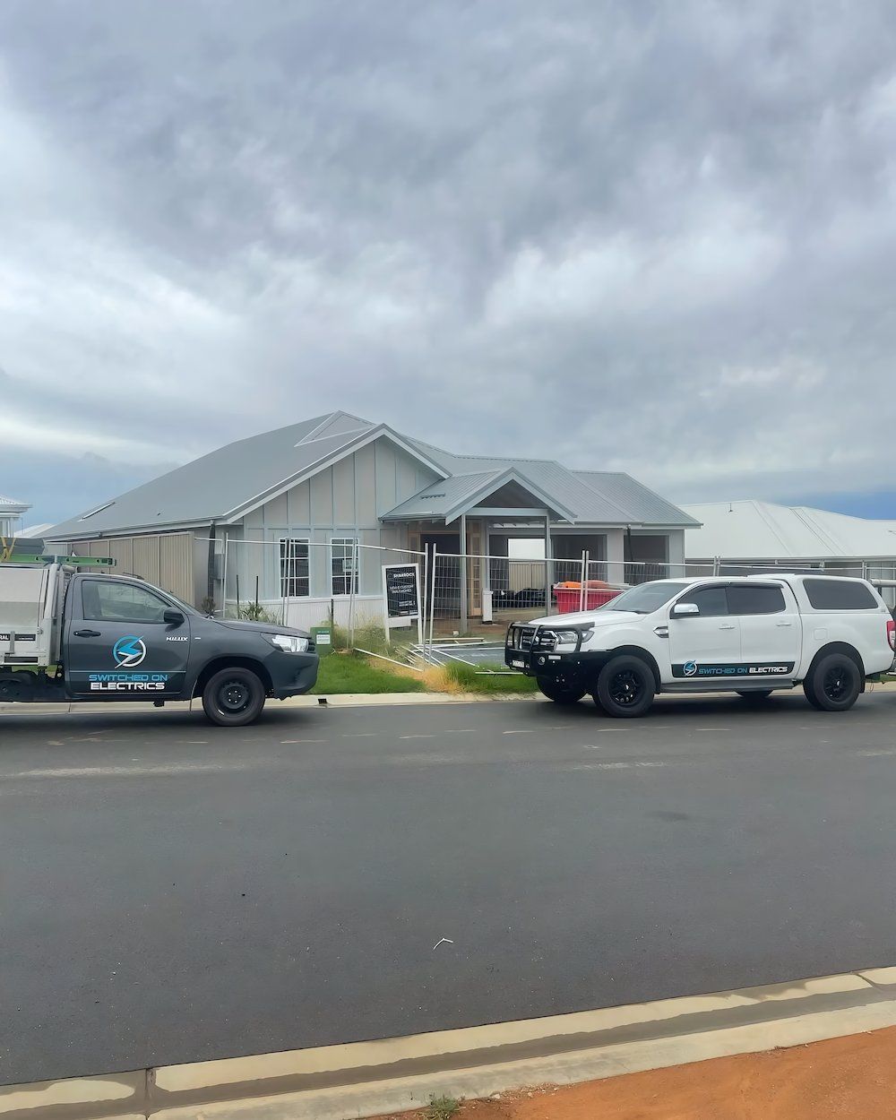 Two Trucks Parked in Front of a House Under Construction — Switched On Electrics in Wagga Wagga, NSW