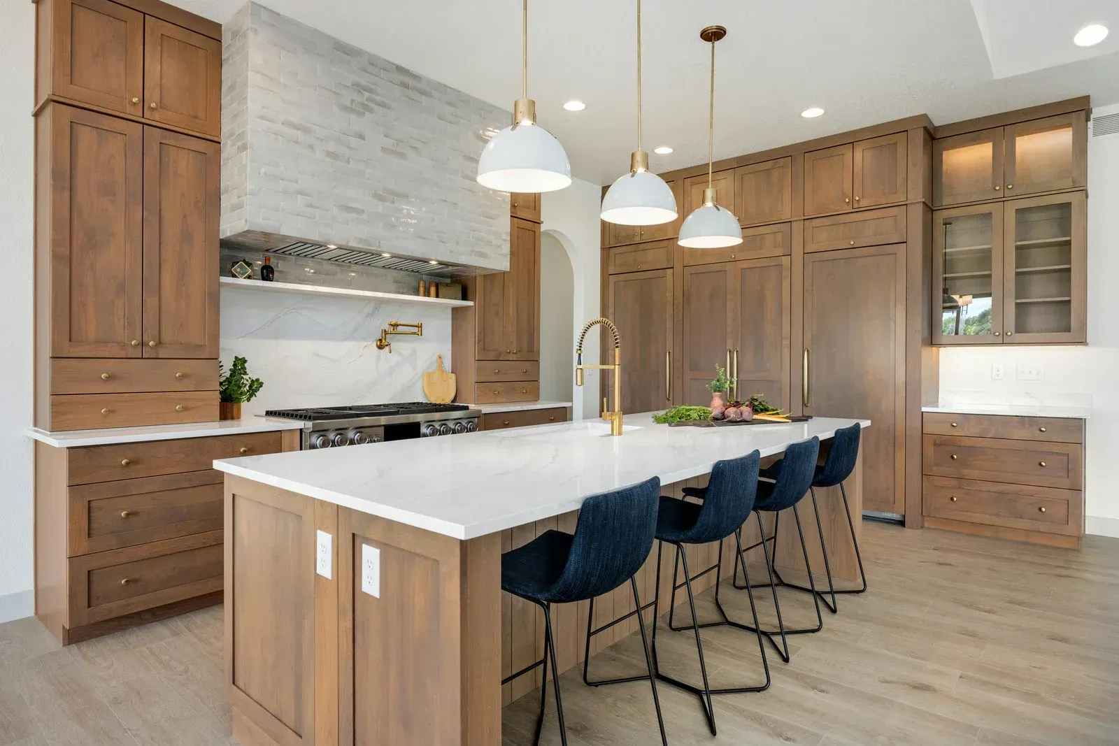 A kitchen with wooden cabinets , white counter tops , and a large island.