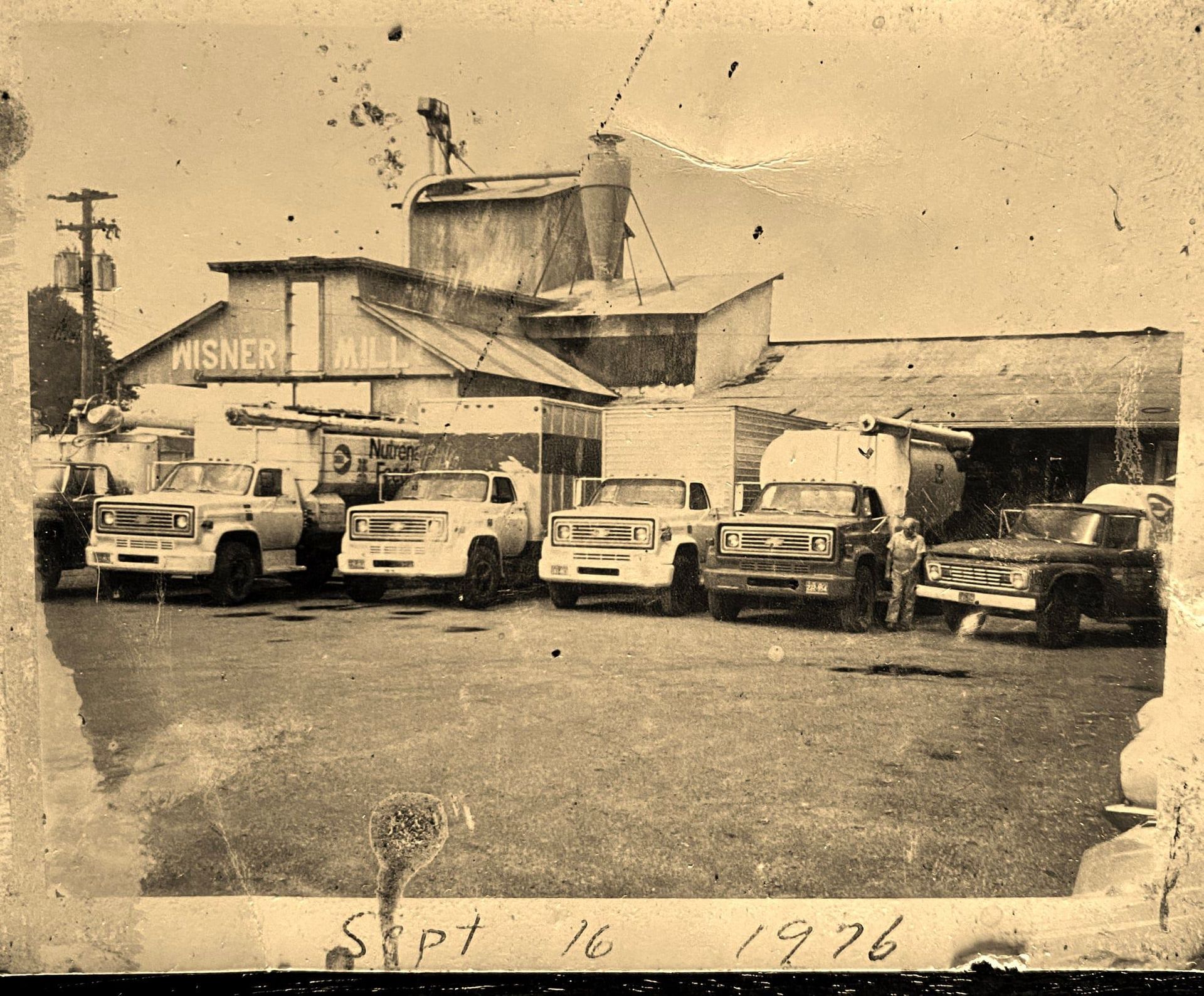 Several trucks are parked in front of a building that says misner mill