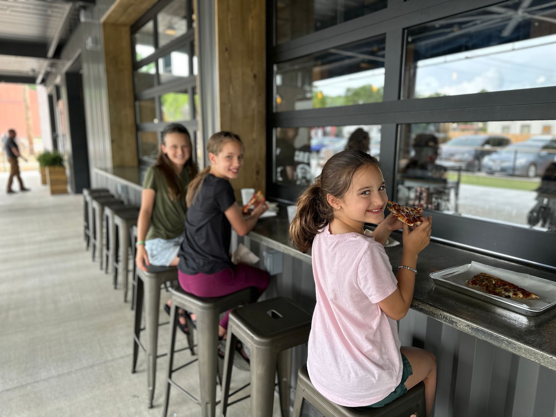Three young girls are sitting at a table eating food.