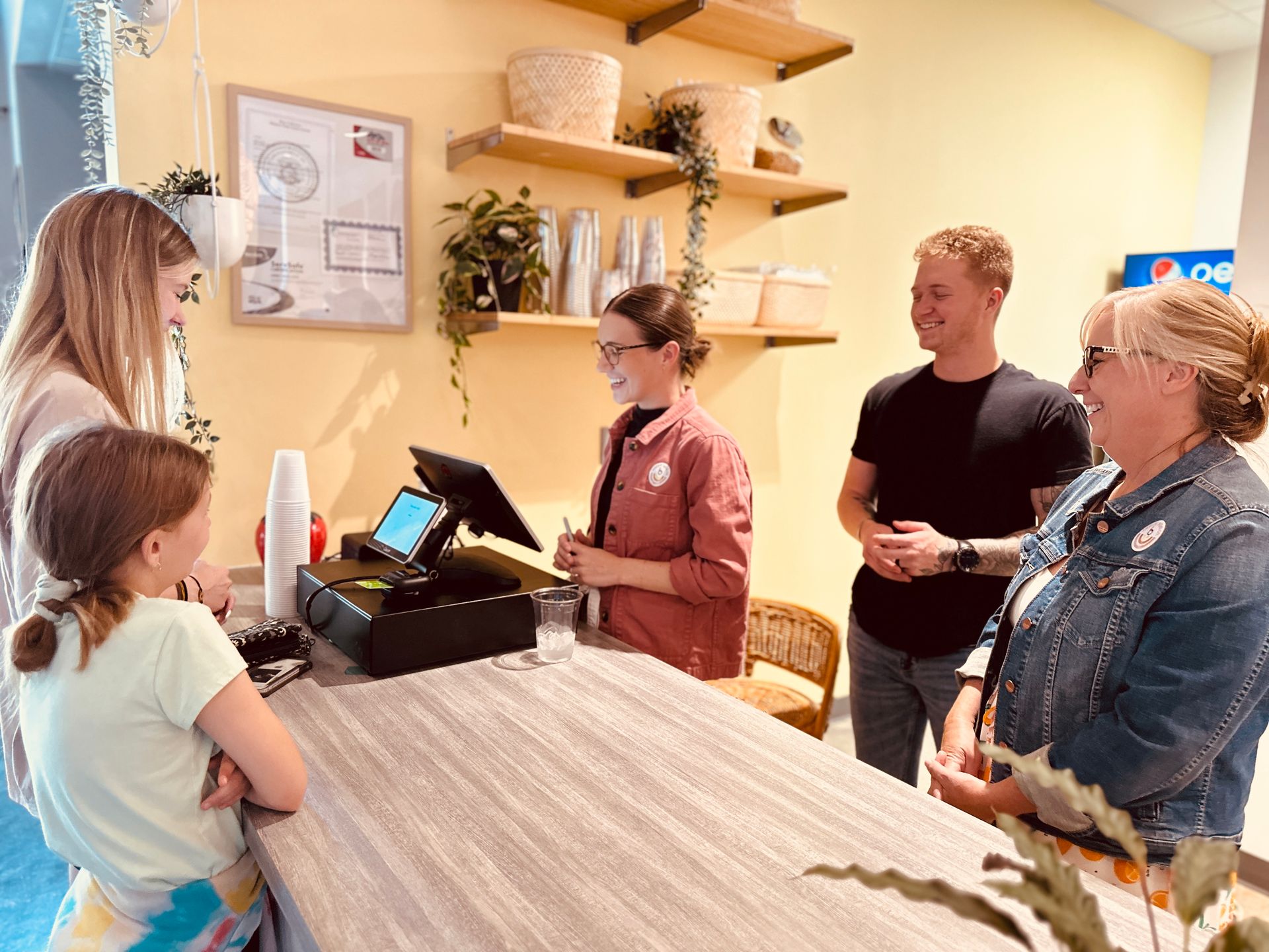 A group of people are standing around a counter in a restaurant.