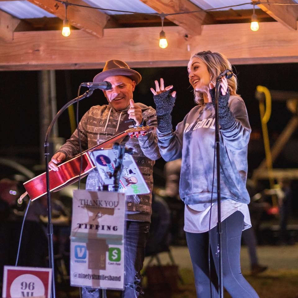 A man playing a guitar next to a woman singing into a microphone