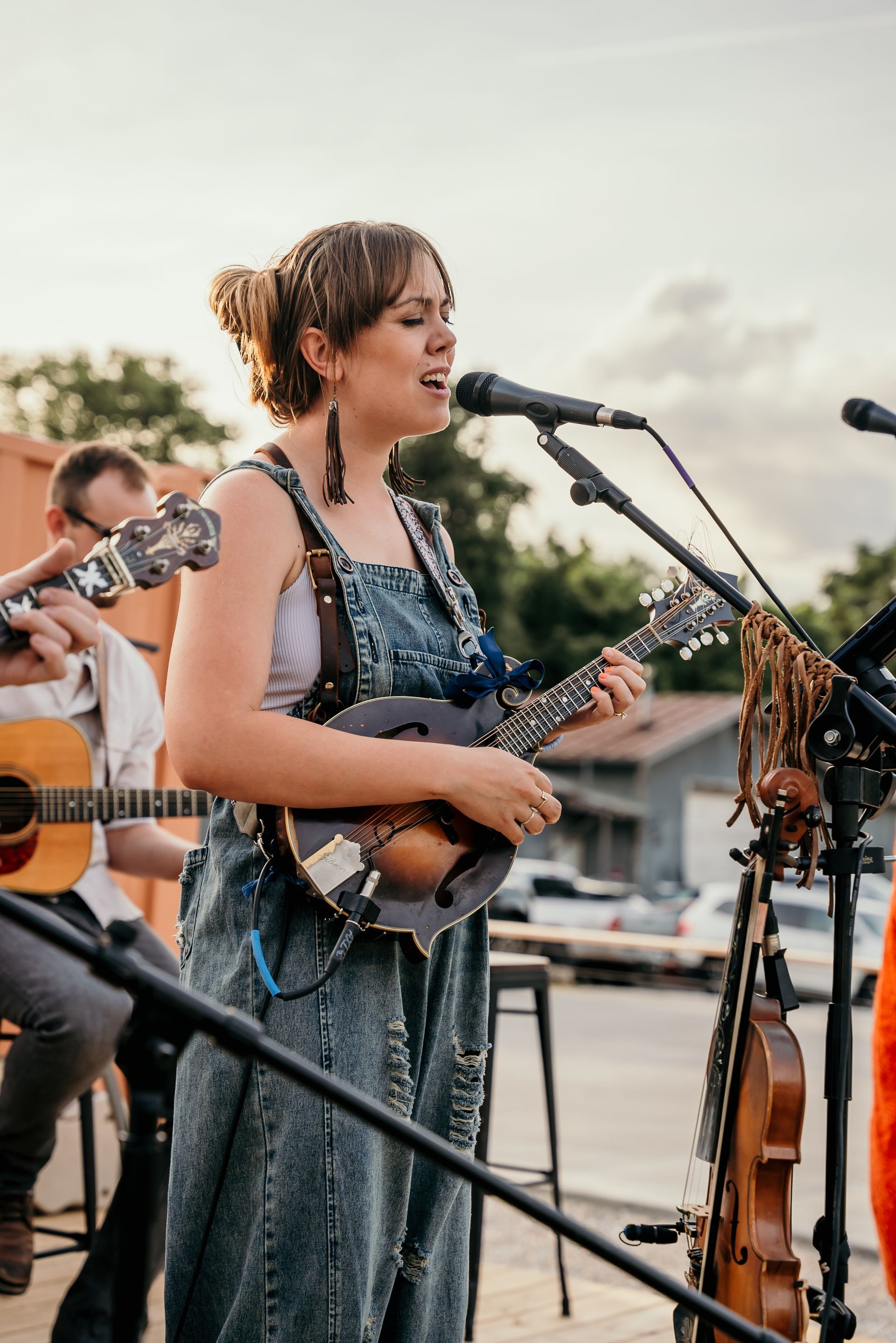 A woman is singing into a microphone while playing a guitar.