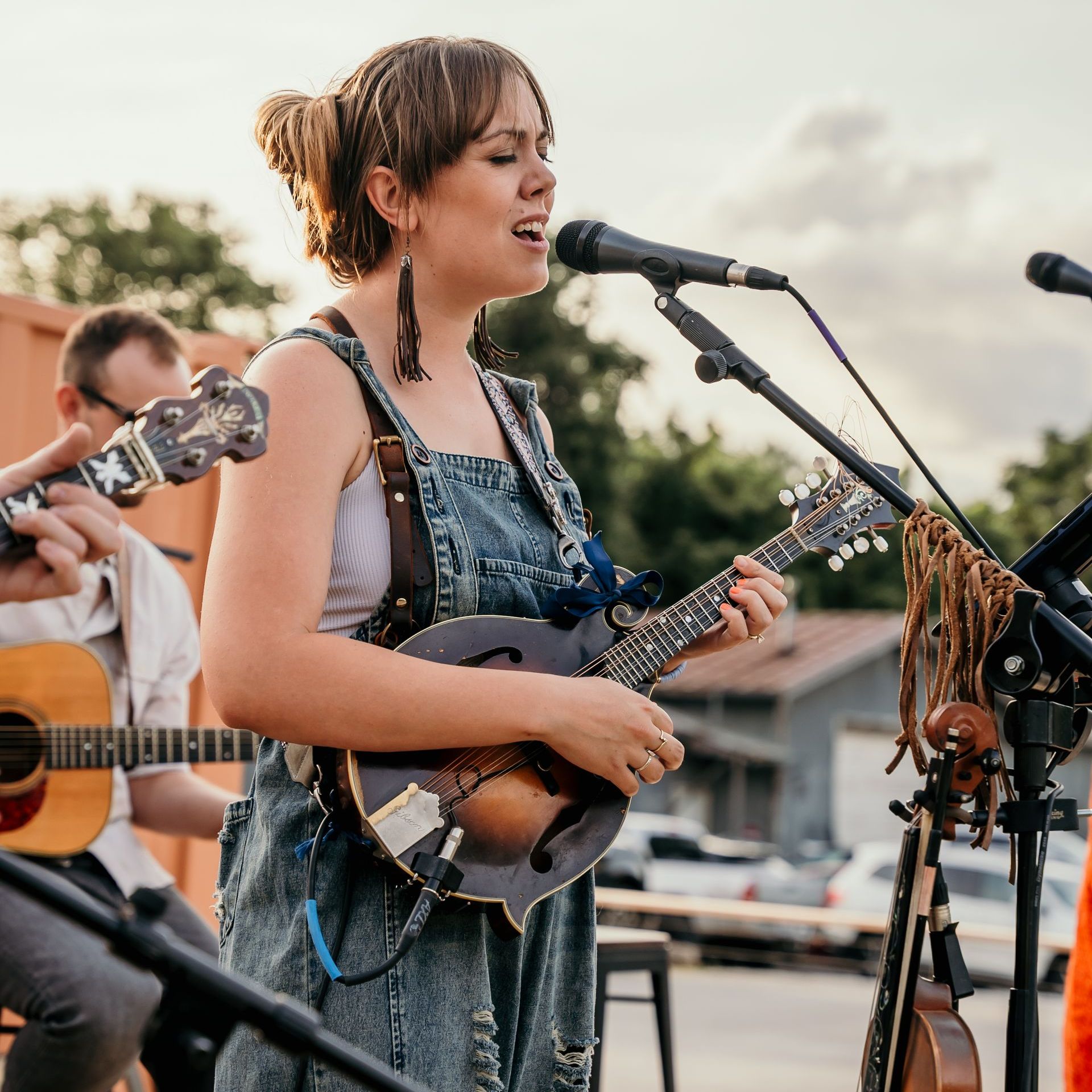 A woman singing into a microphone while playing a guitar