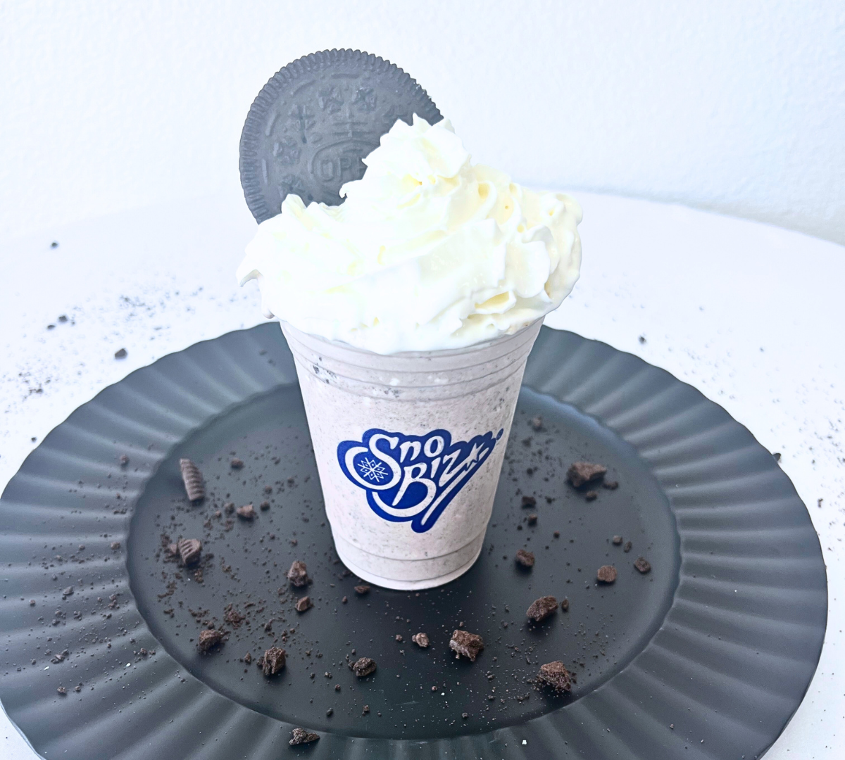 A cup with whipped cream and an oreo cookie on top of it