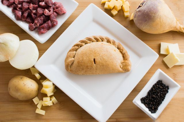 A white plate topped with a pastry and vegetables on a wooden table.
