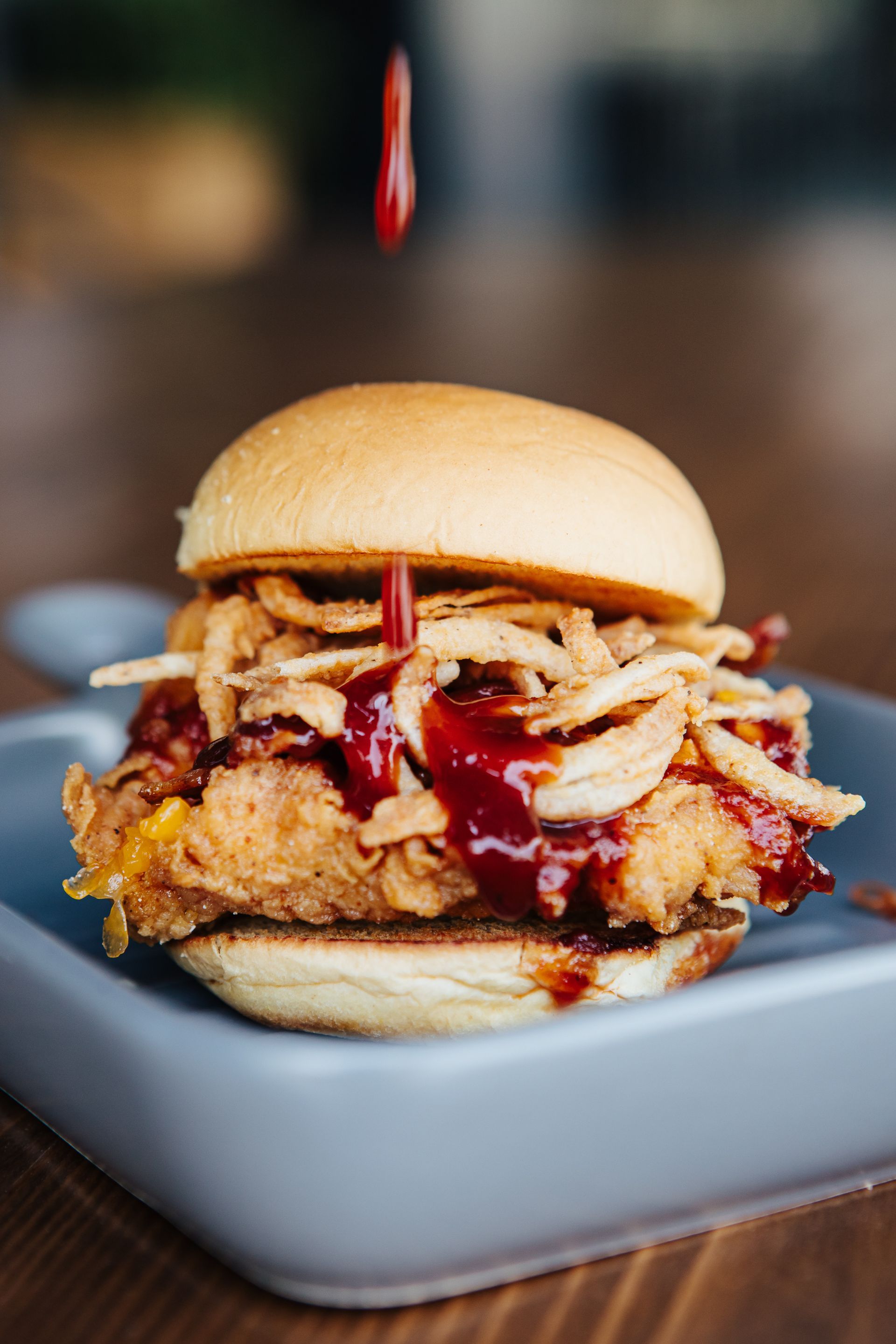 A close up of a chicken sandwich on a plate on a table.