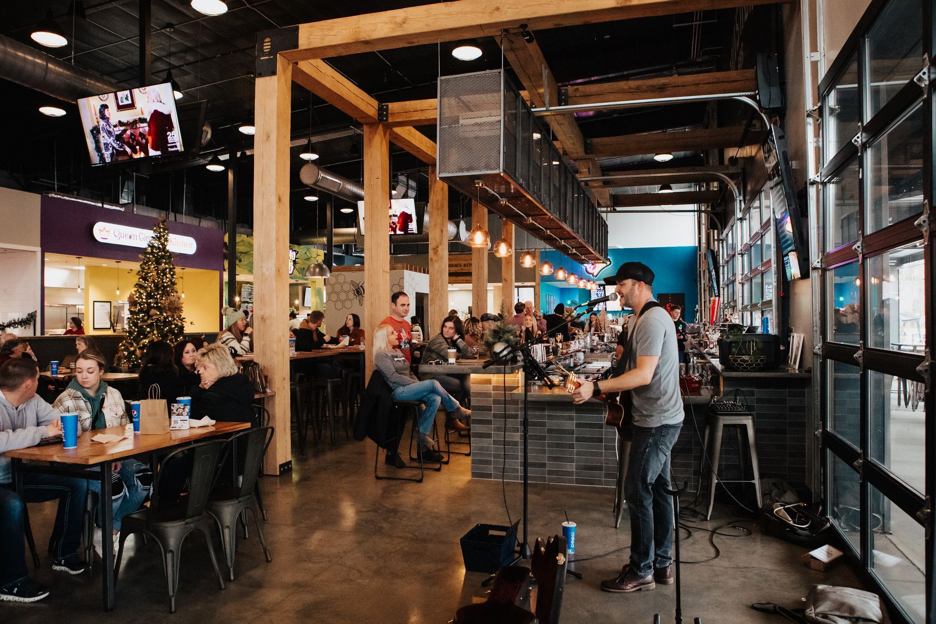 A man is playing a guitar in a restaurant while people sit at tables.