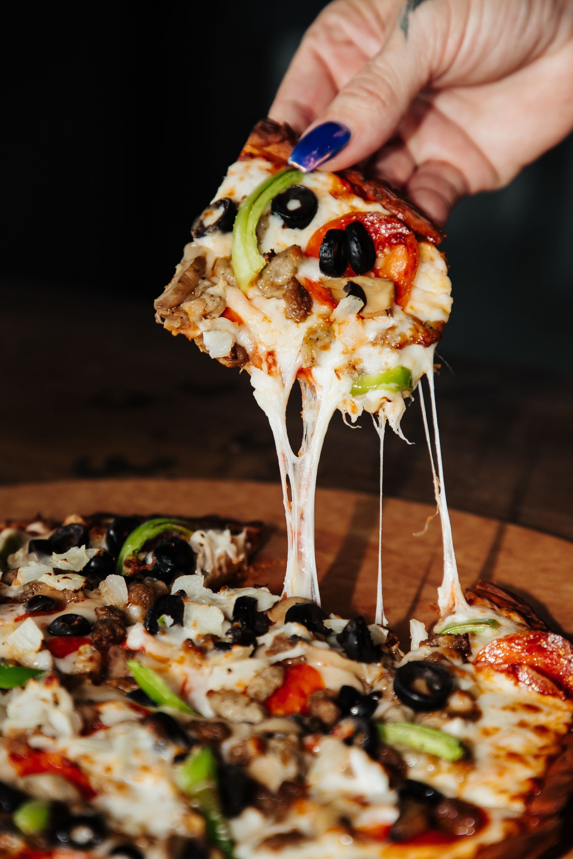A person is taking a slice of pizza from a pizza.