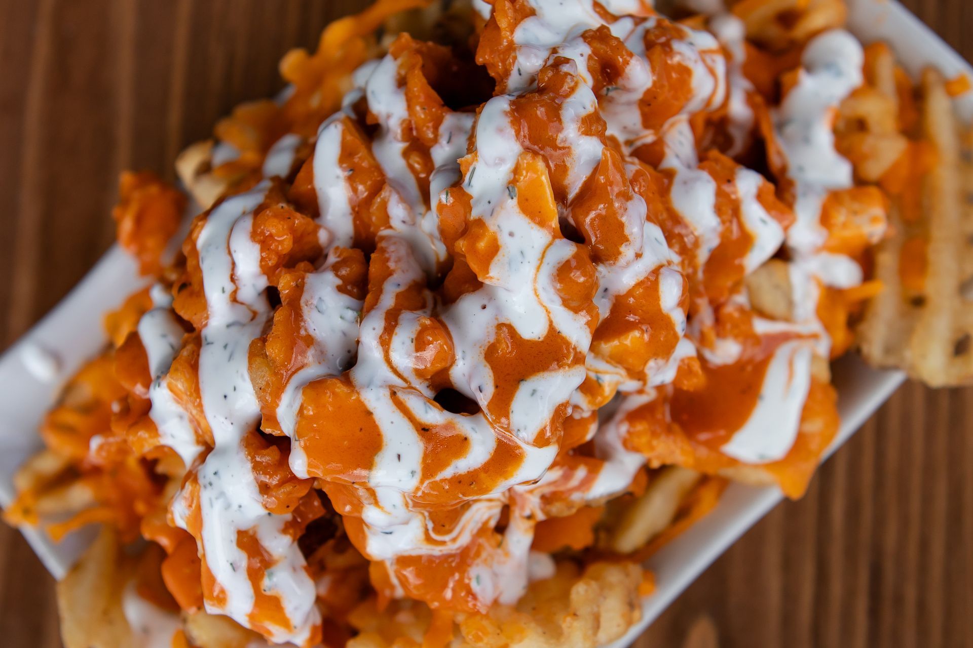 A close up of a plate of food with fries and sauce on a table.
