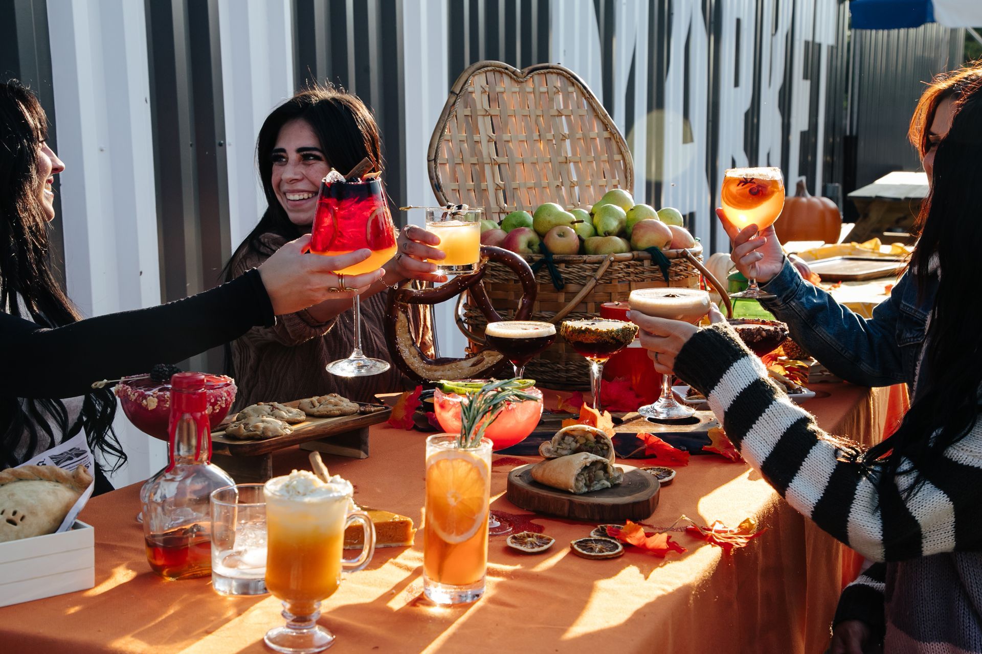 A group of women are sitting at a table holding drinks.