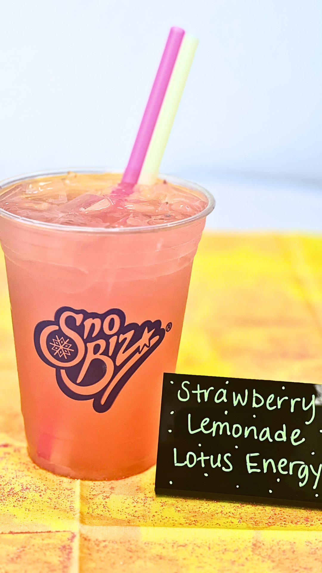 A cup of strawberry lemonade with a straw on a table.
