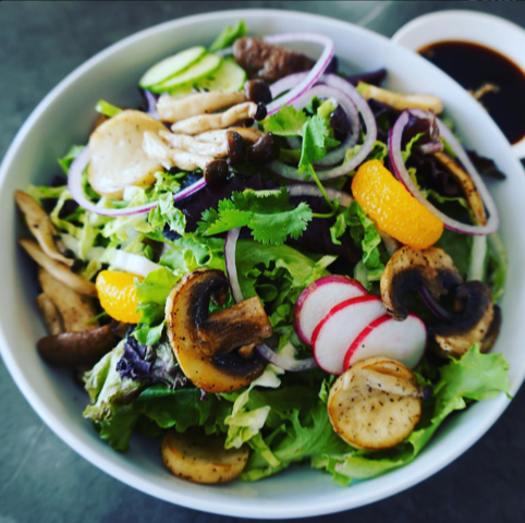 A salad with mushrooms onions and radishes in a white bowl
