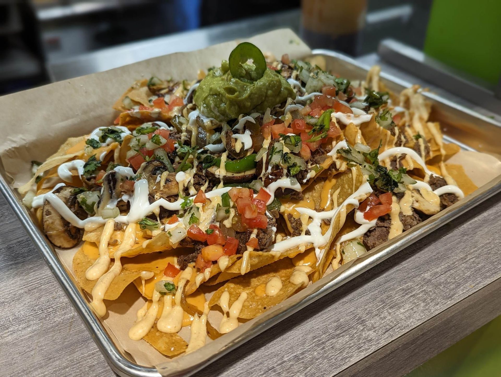 A tray of nachos with guacamole , salsa , and cheese on a table.