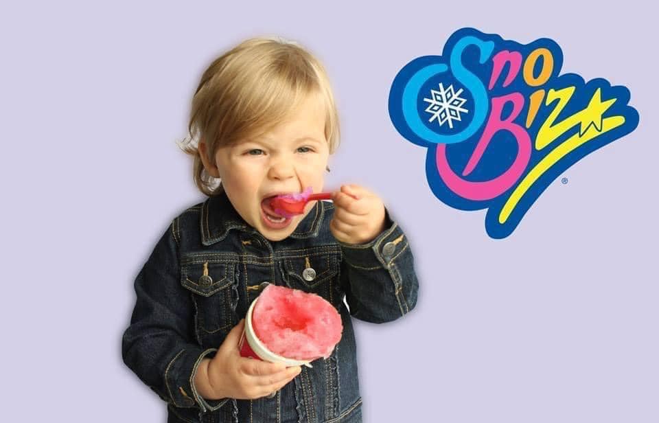 A little girl is eating ice cream from a cup with a spoon.
