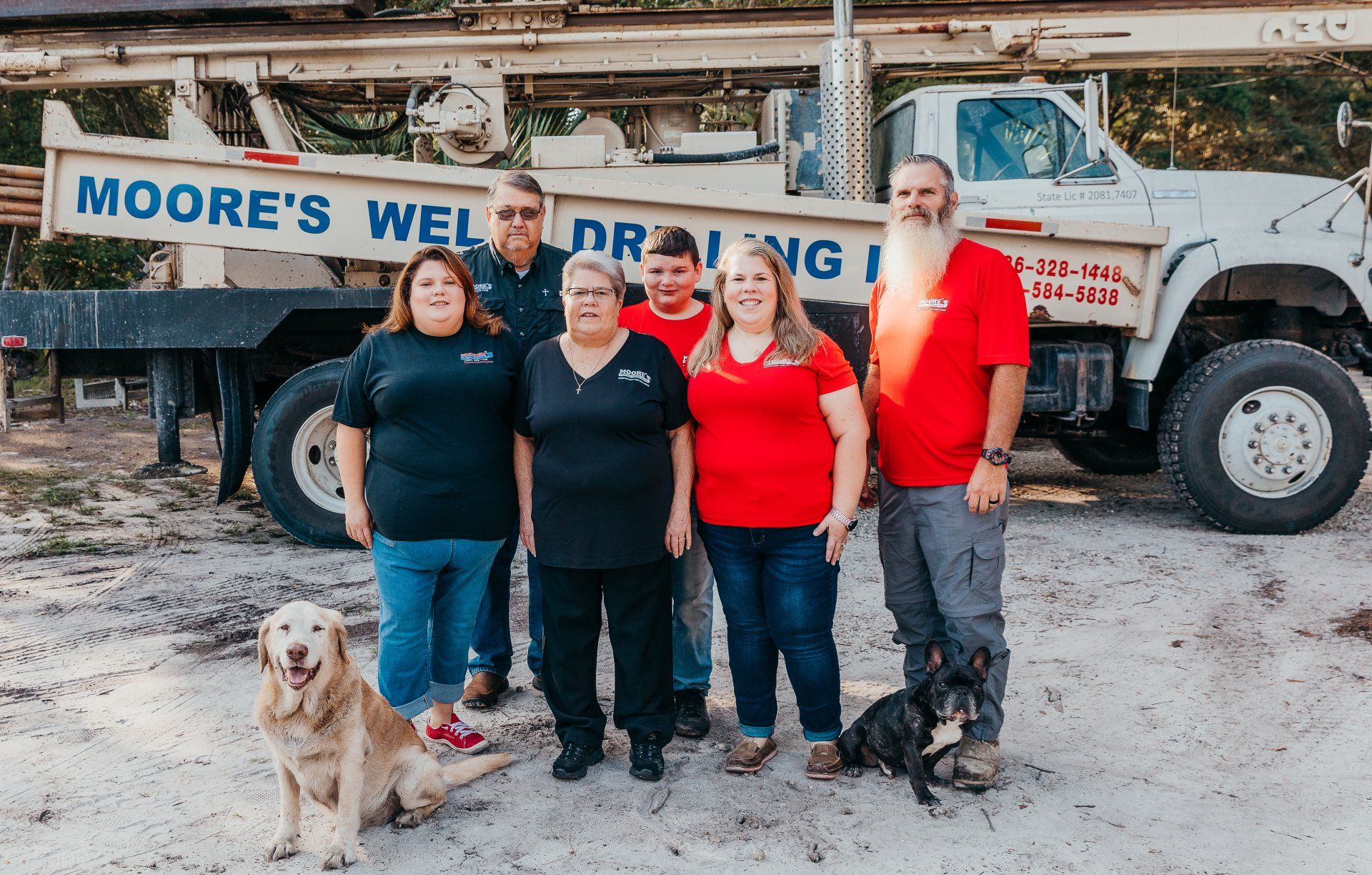 A Family Picture — Palatka, Fl — Moore’s Well Drilling Group of people posing with dogs in front of a Moore's Well Drilling truck.