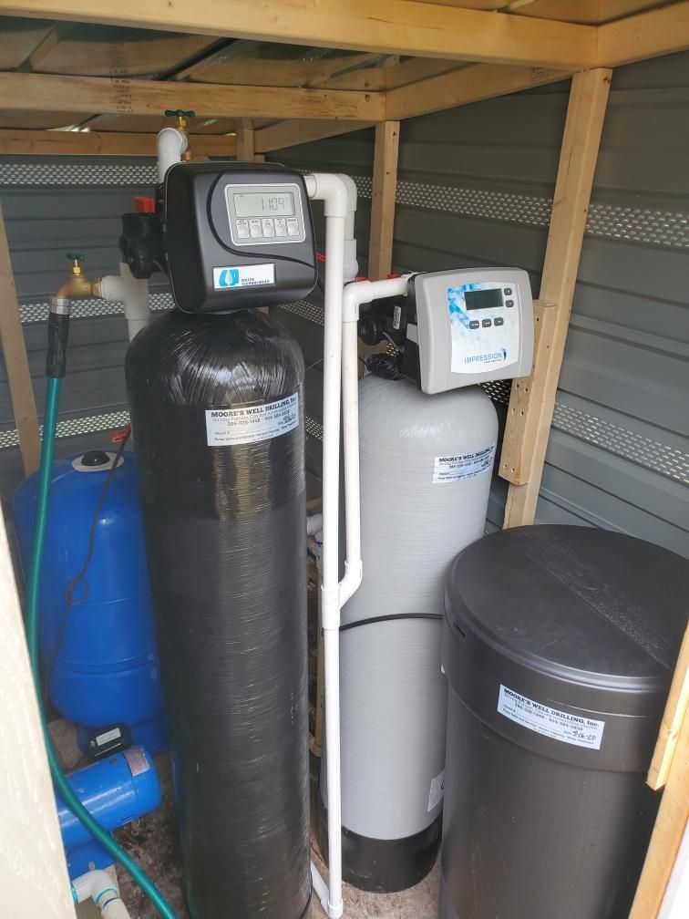 Water Tank In Different Sizes — Palatka, Fl — Moore’s Well Drilling Water filtration system in a shed, featuring black and white tanks and blue tank.