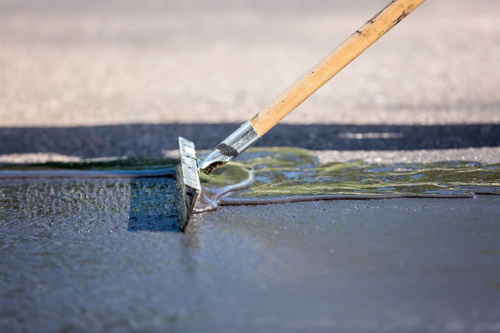 Driveways Sheffield using a rubber blade to spread selant over a driveway in Sheffield