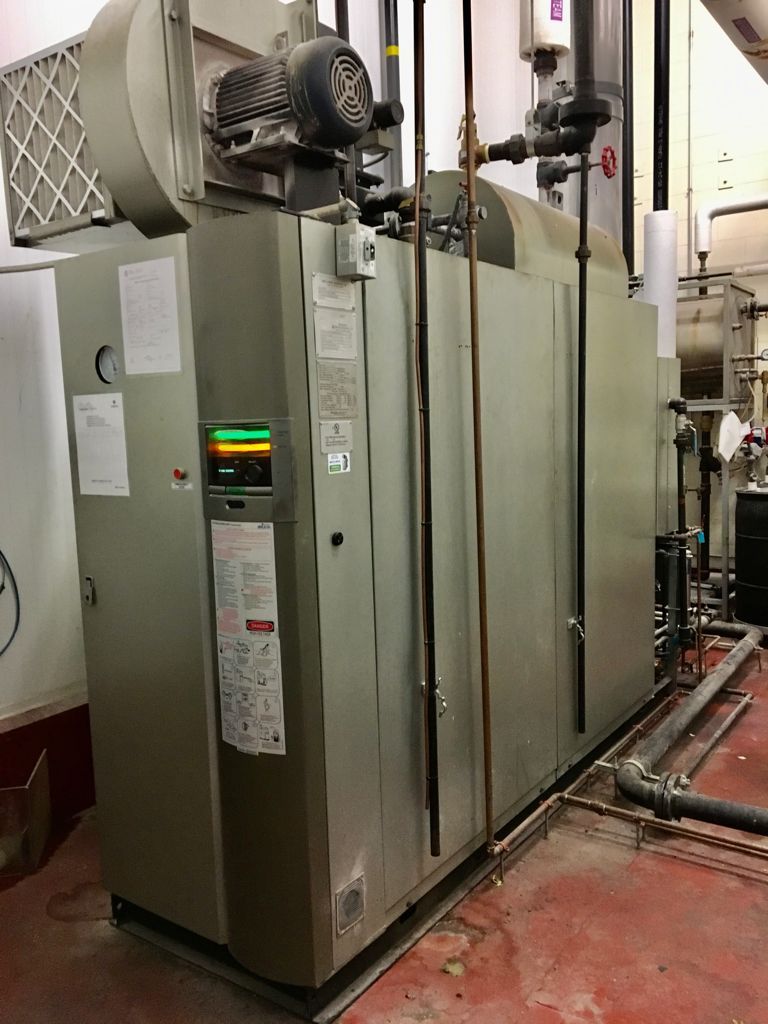Large, gray industrial HVAC unit in a utility room with red flooring.