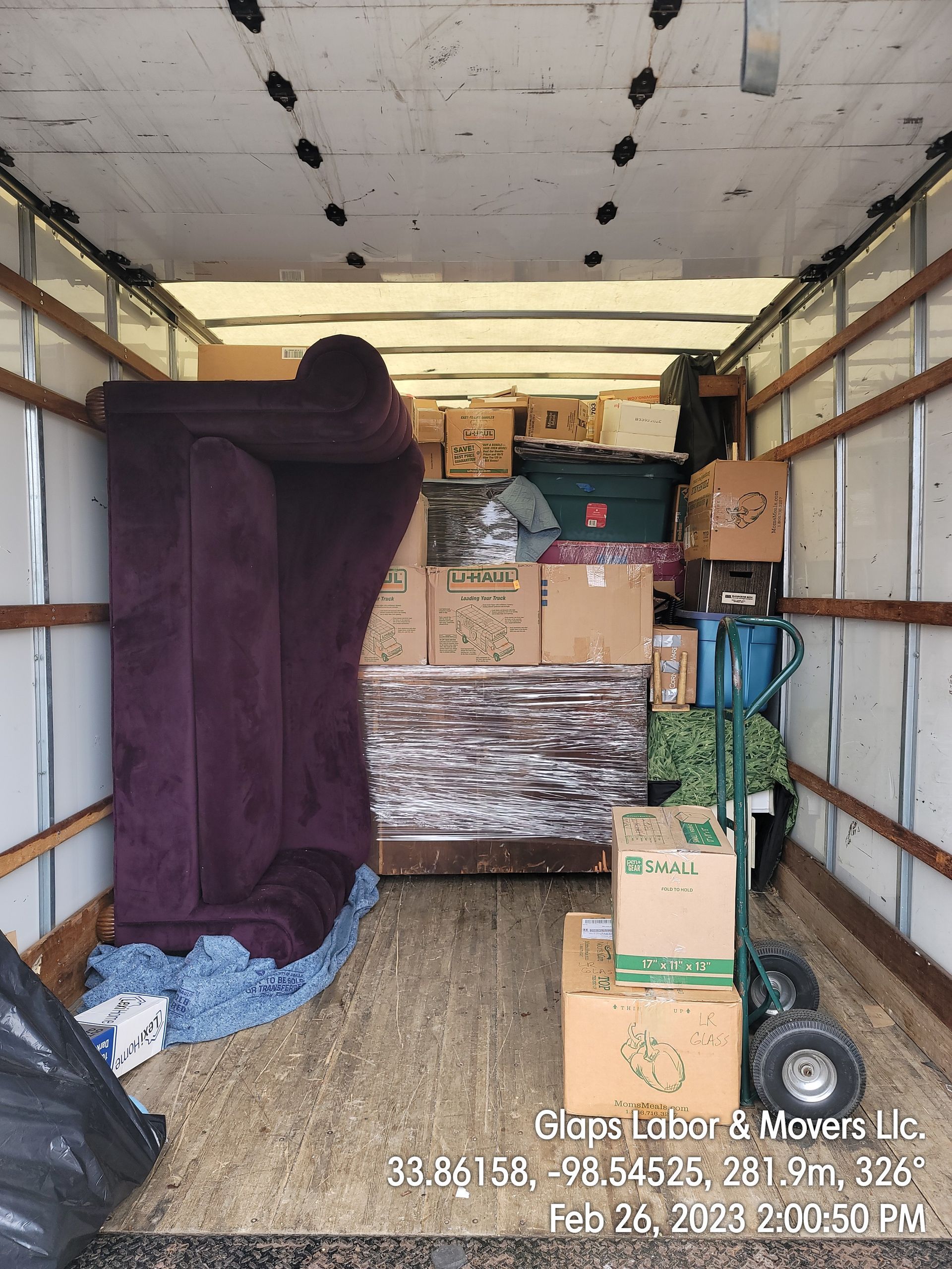 Inside of a moving truck loaded with furniture, boxes, and other items.