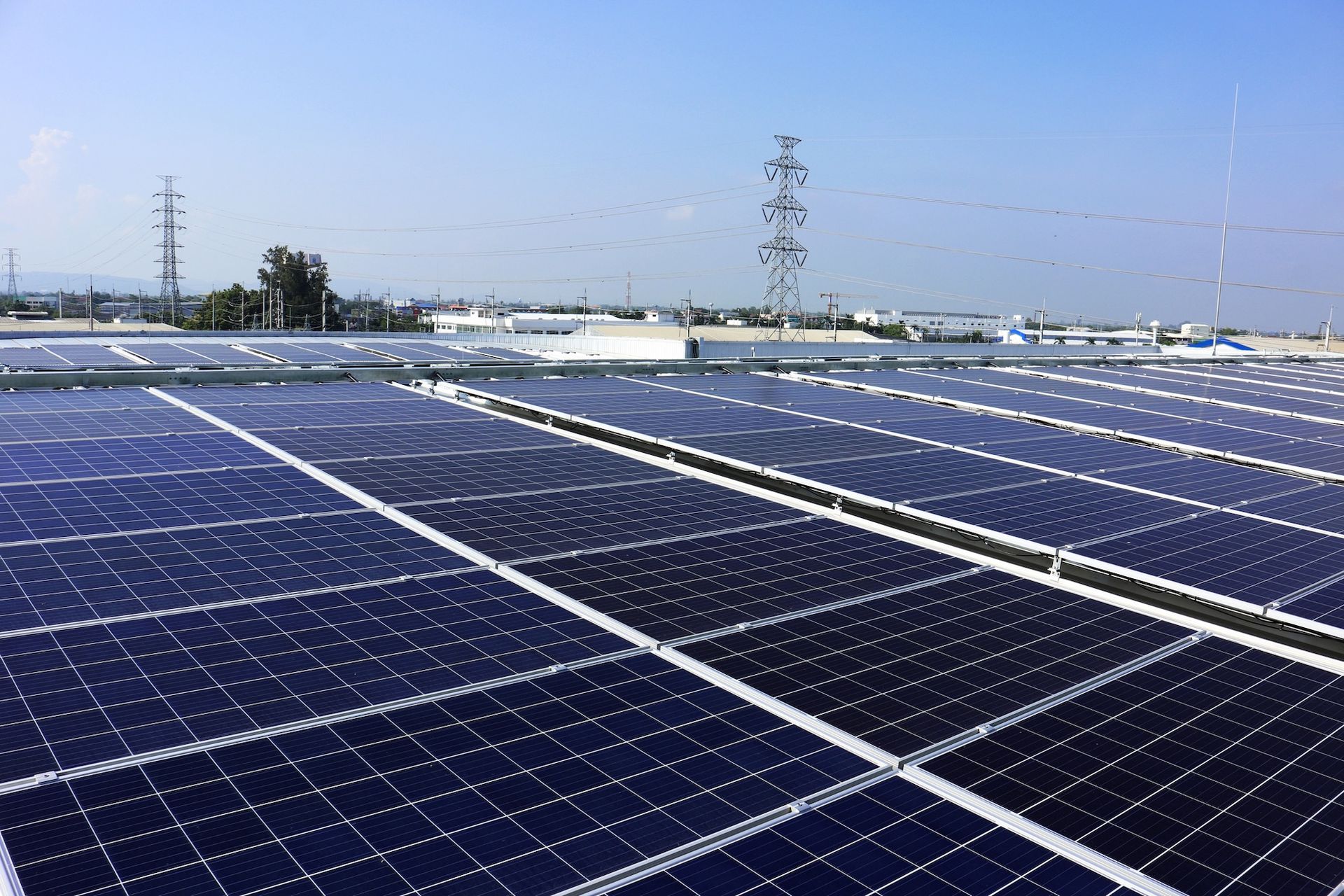 Rooftop solar panels, blue and black, generating electricity. Clear sky, industrial setting.