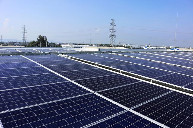 Rooftop solar panels, blue and black, generating electricity. Clear sky, industrial setting.