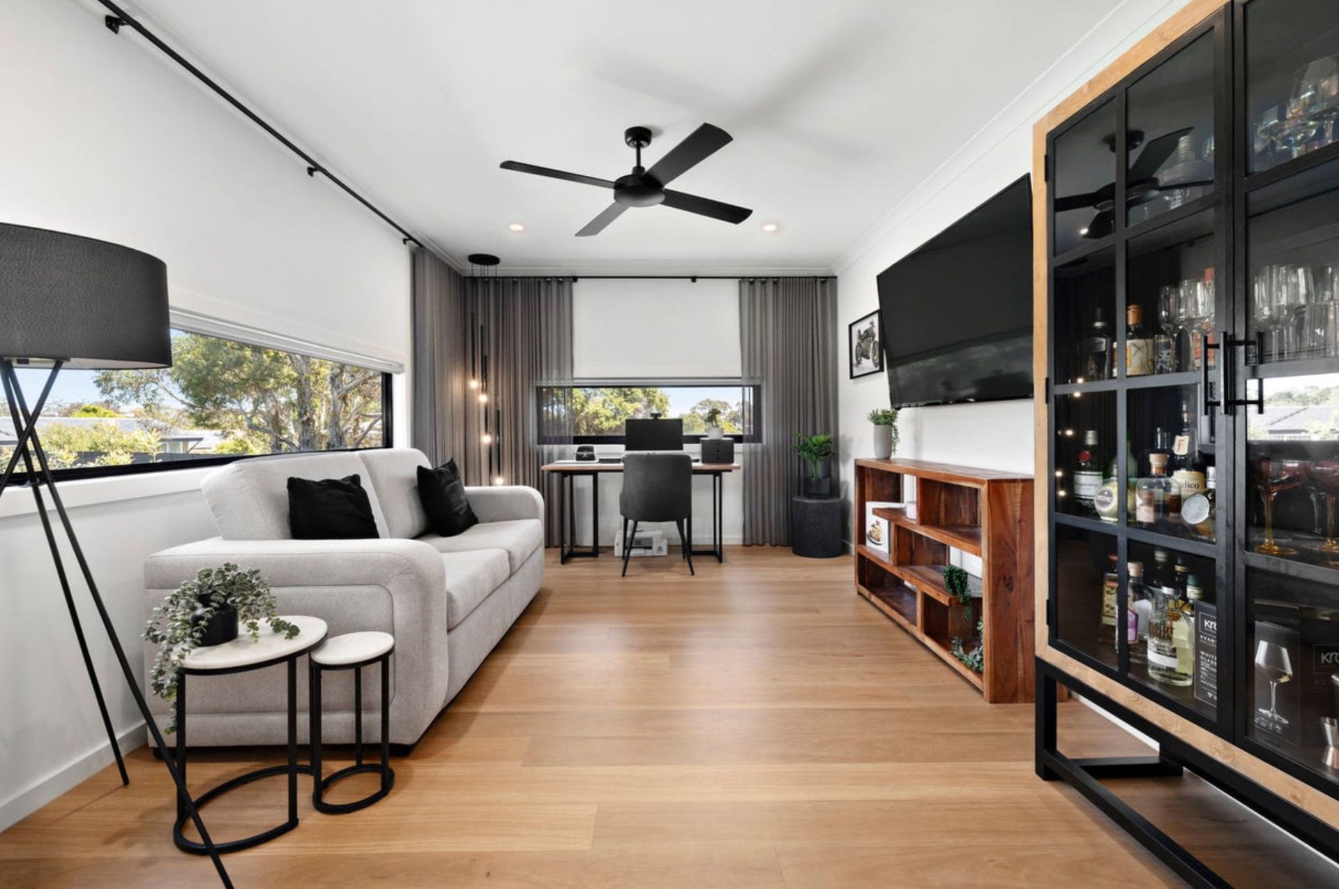 Living room with grey sofa, wooden floor, and black cabinet.