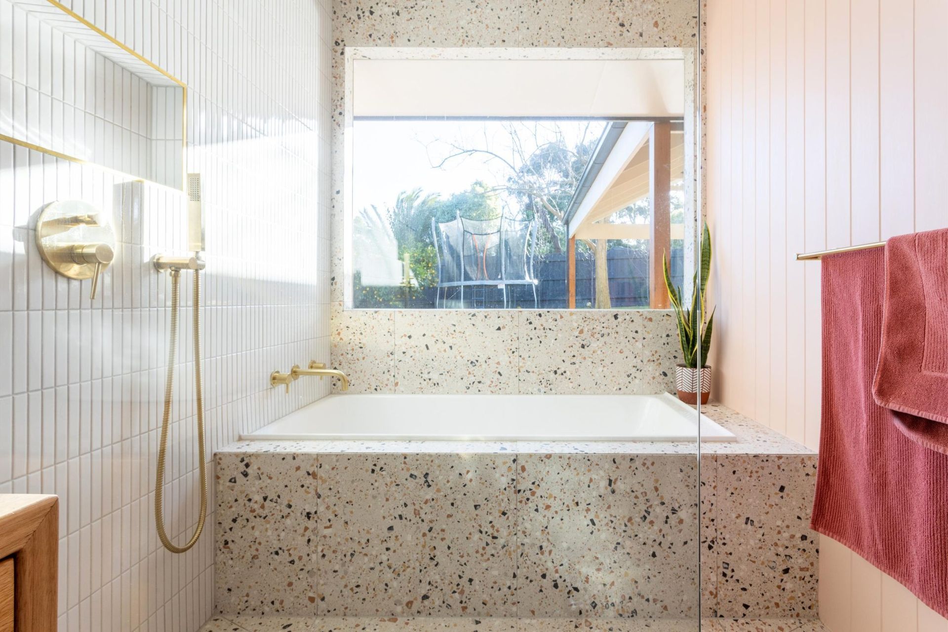 Bathroom with white and speckled walls, a bathtub, and pink towels.