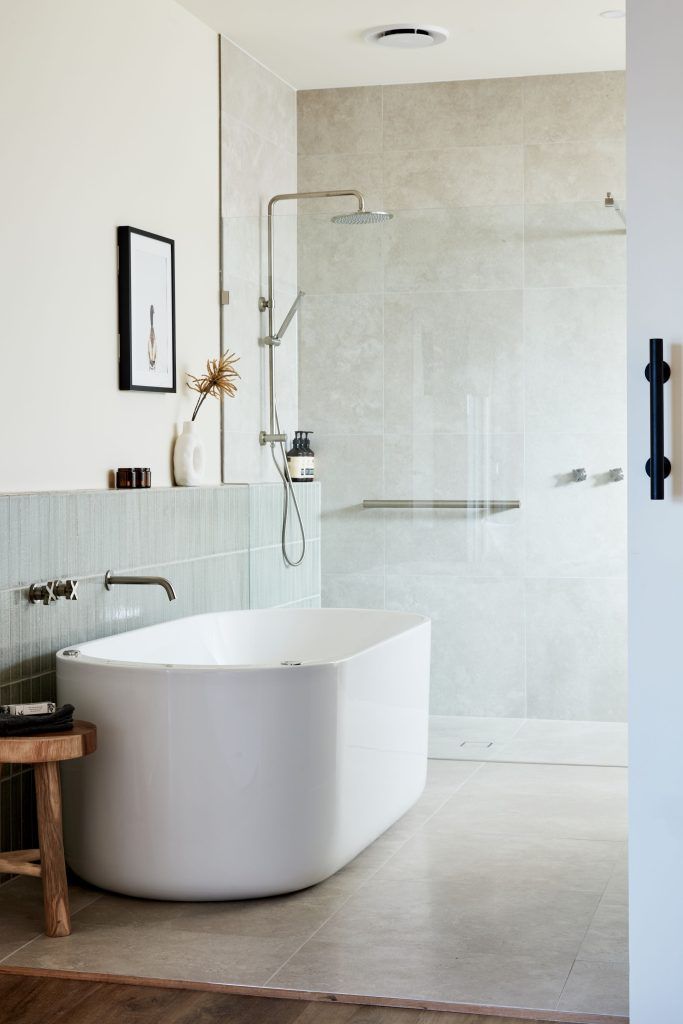 Bathroom with a white tub, walk-in shower, and light gray tiled walls.