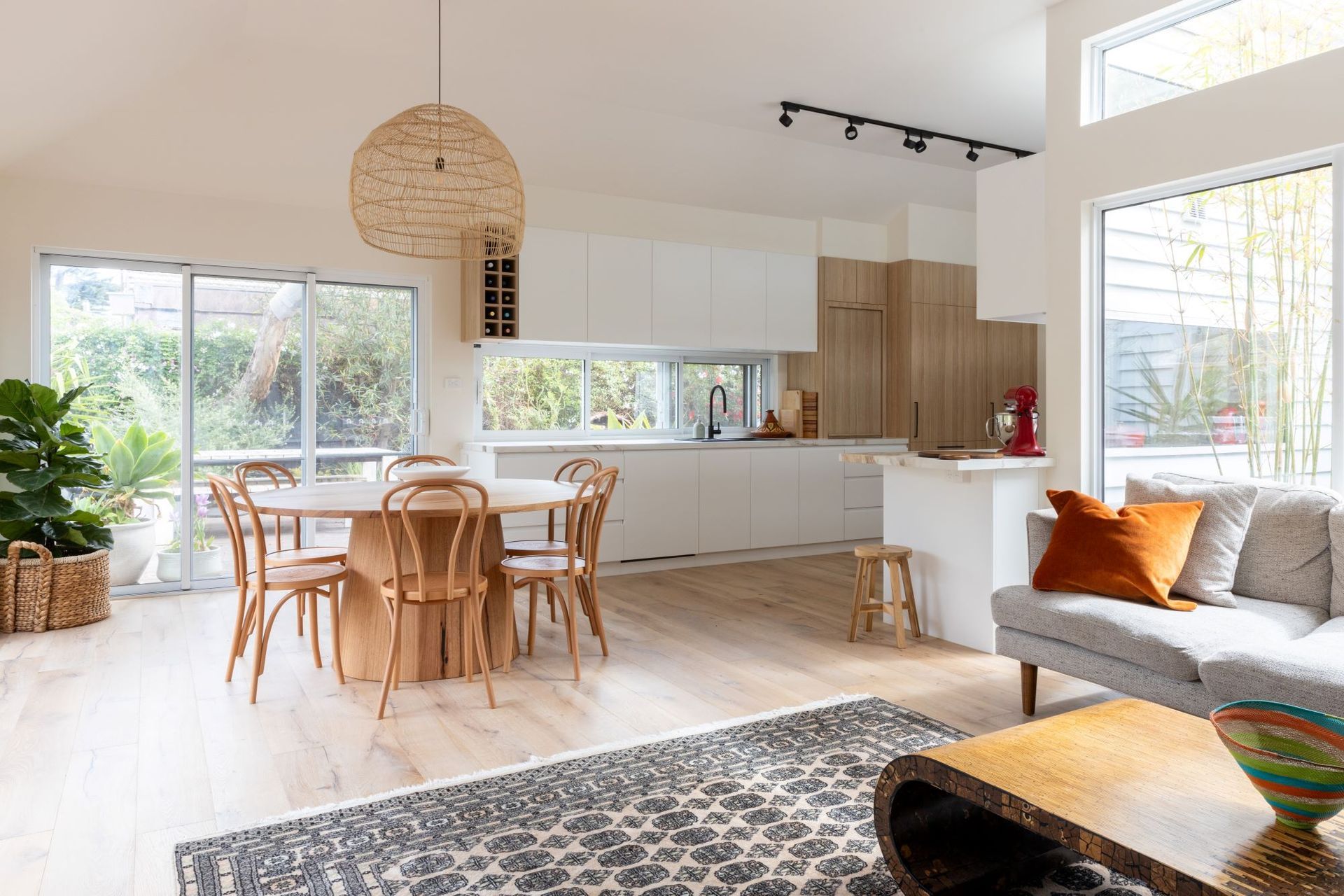 Bright, open-concept kitchen and dining area with wooden table, modern kitchen, and sliding glass doors to a garden.