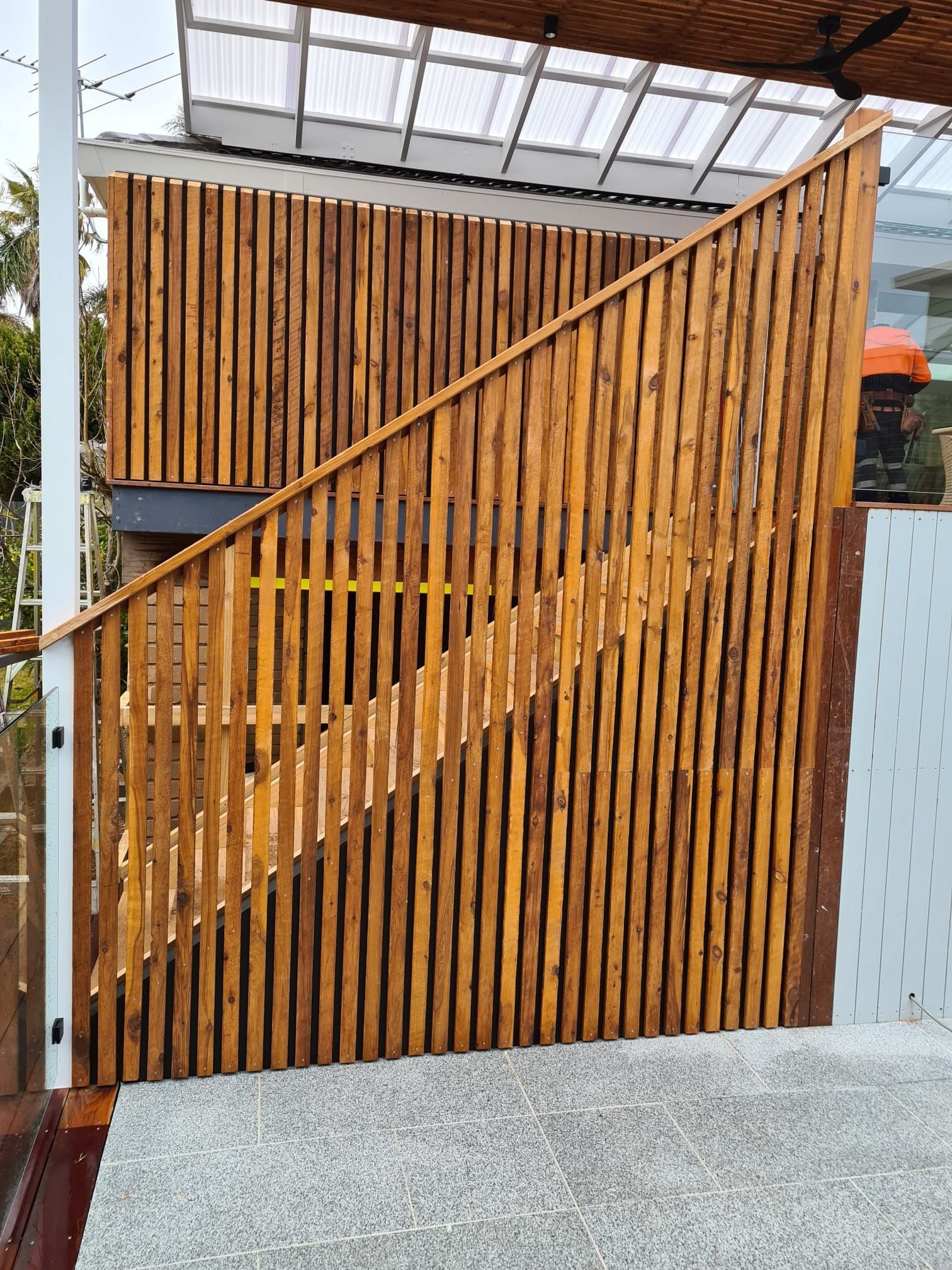 Wooden slatted fence with stairs and a white railing.