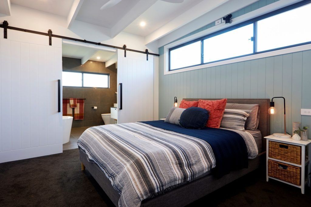 Bedroom with bed, sliding barn doors, light blue wall, and small nightstand.