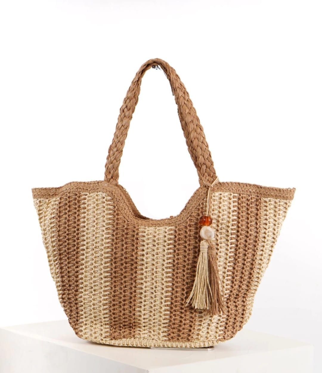 Bolso tote de paja tejida con asas trenzadas, rayas bicolor y detalle de borlas.