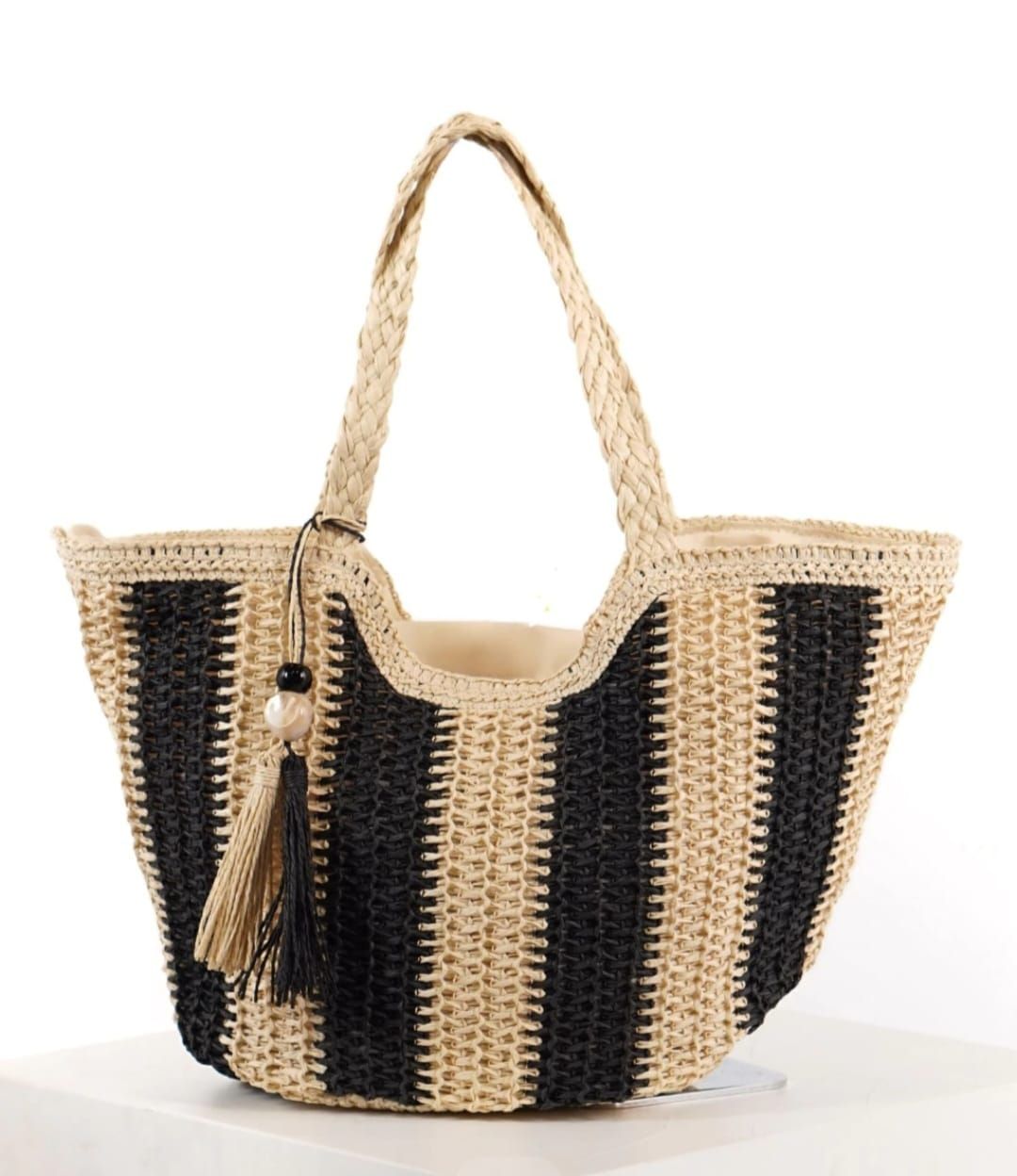 Bolso tote tejido a rayas negras y beige con asas trenzadas, borla y detalle de cuentas.