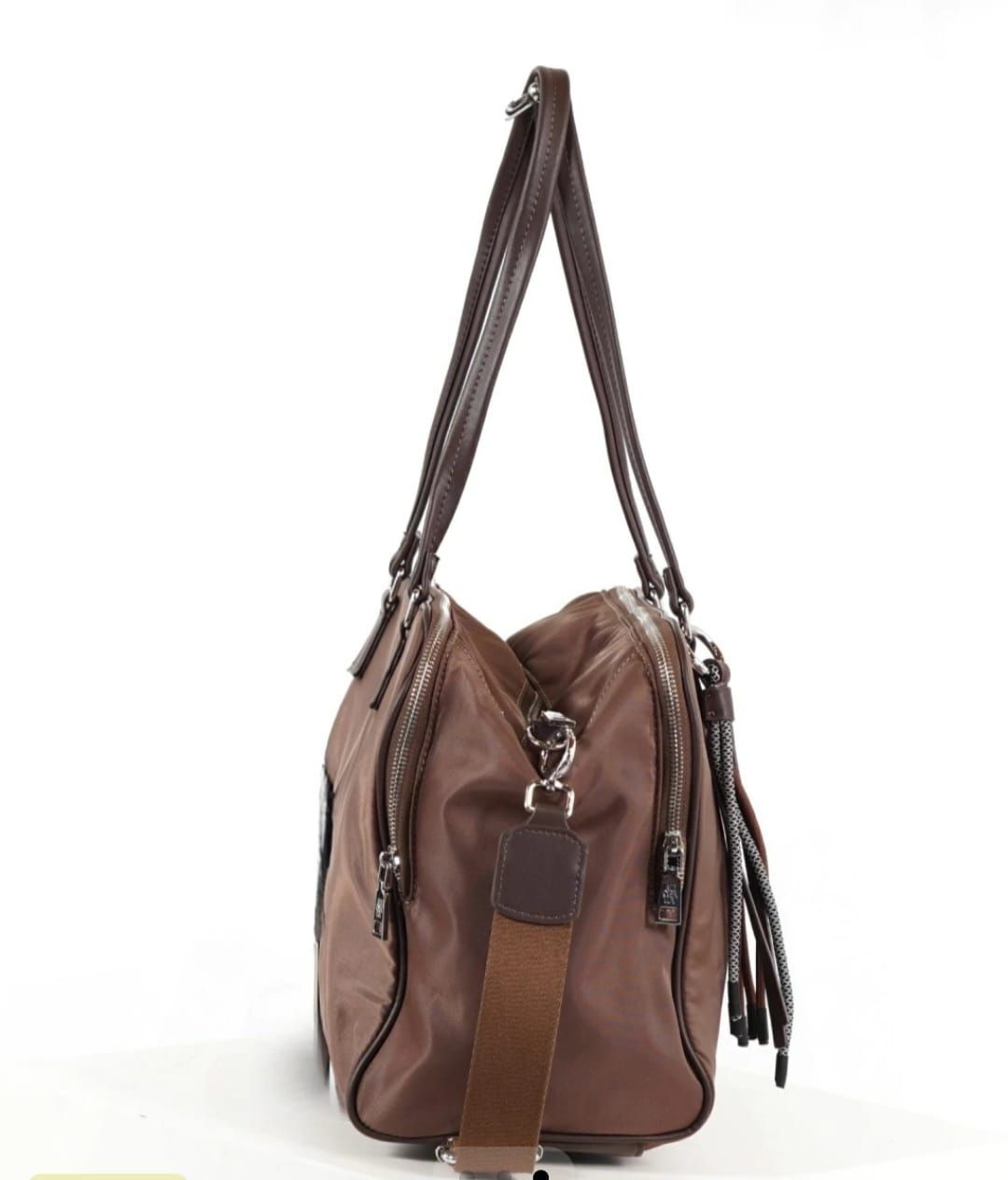 Mujer sosteniendo un bolso marrón, vistiendo una chaqueta color crema, mirando hacia la cámara.