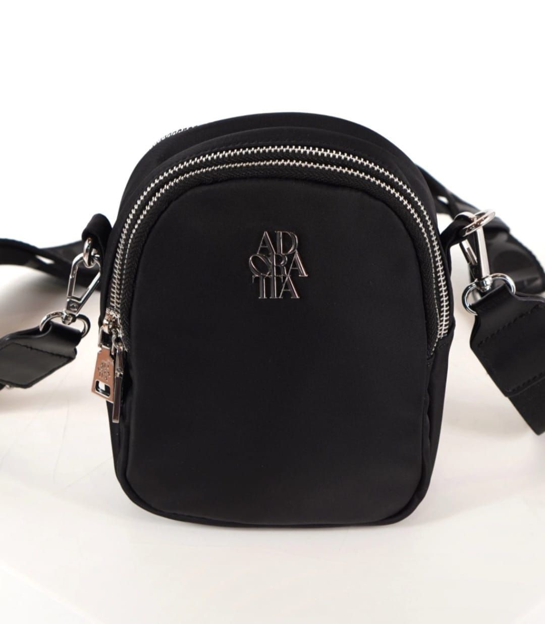 Bolso bandolera de color negro con dos compartimentos con cremallera y logo plateado.