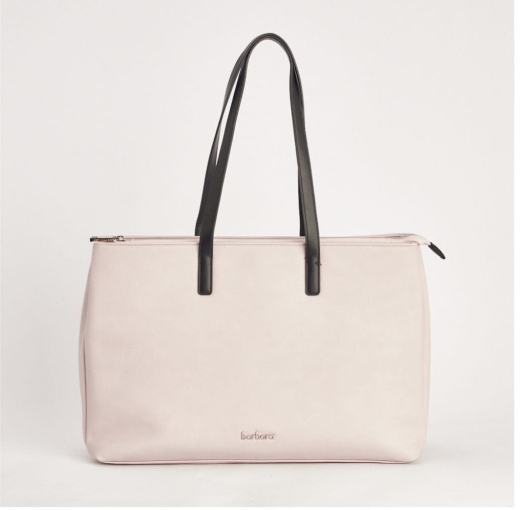 Bolso de mano de color rosa con tiras negras sobre fondo blanco.