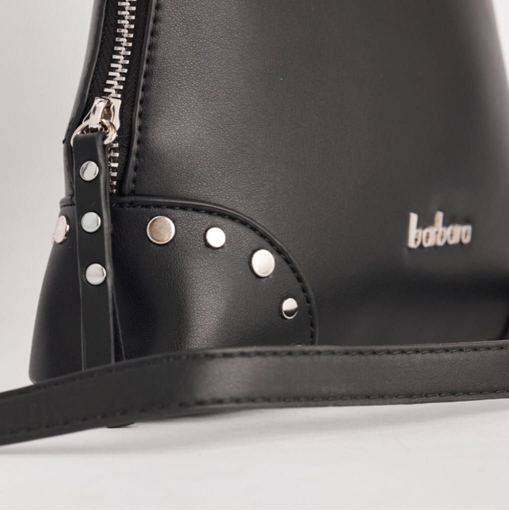 Bolso de mano negro en forma de cúpula con asa superior y correa para el hombro; detalle de tachuelas plateadas y cremallera.